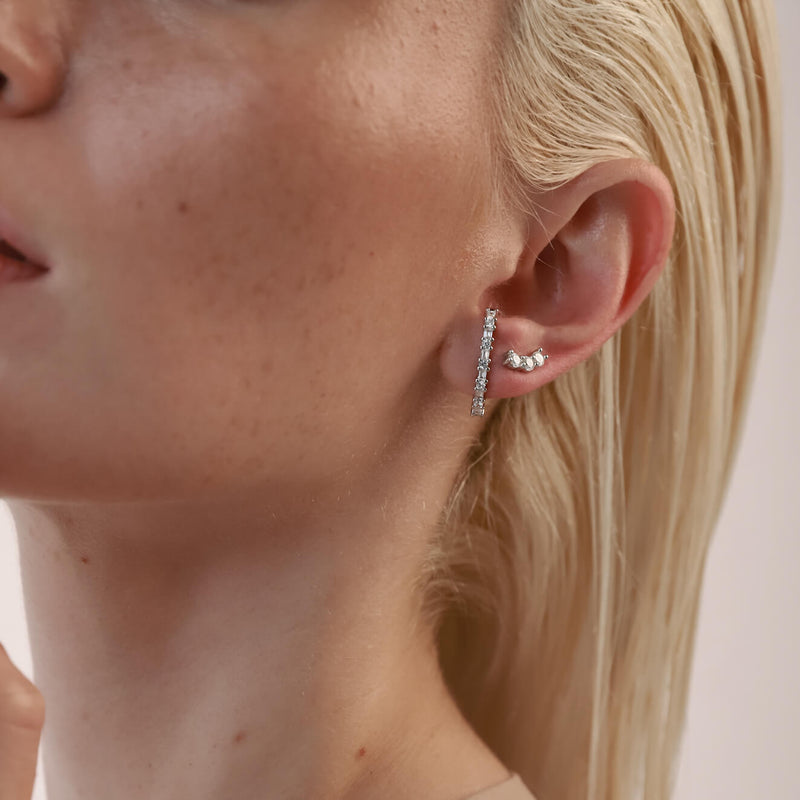 Model wearing the Comet's Trail Ear Stud made of sterling silver zirconia filled stud and a smaller three zirconia stud earrings.