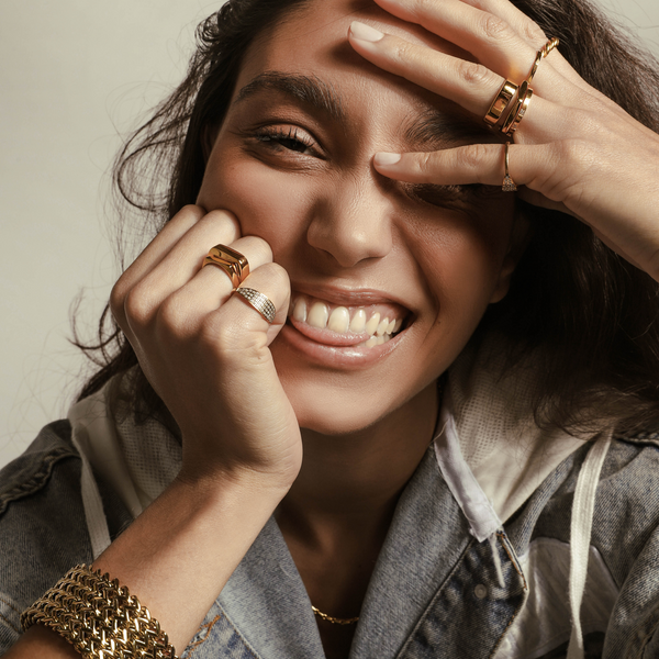 Model wearing The Thin RING which is an 18k Gold plated dainty thin ring stacked with the rectangle ring. She is also wearing other artizan rings and the braided chain cuff.