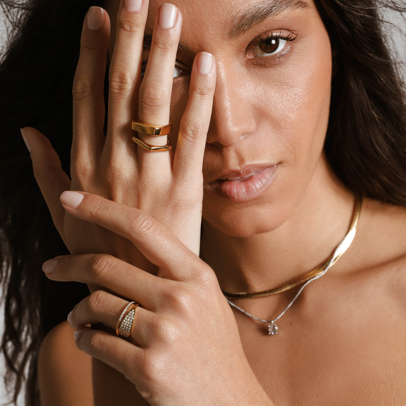 Model wearing The CHIC SNAKE NECKLACE which includes 2 necklaces. A Rhodium-plated stainless steel chain with Solitaire 1ct zirconia and Stainless steel 18k gold plated snake necklace.  She is also wearing the SHAPE STACK RING, SEEDS Ring and another ring filled with cubic zirconia.