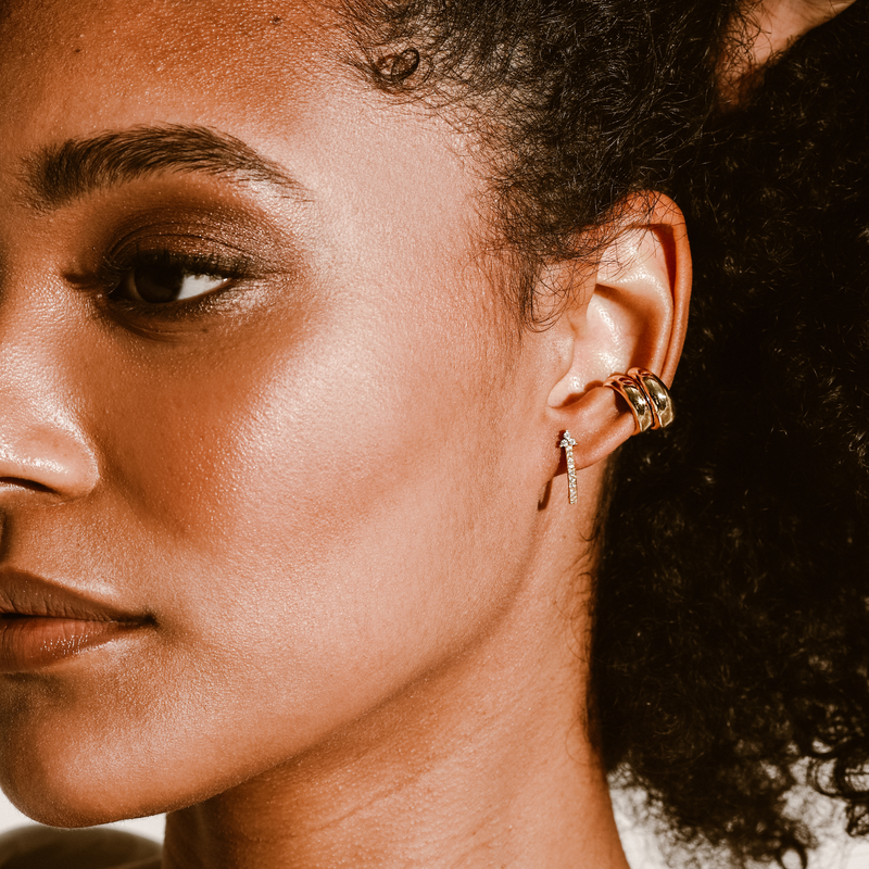 Model wearing the SAVERS EAR CUFF which comes with two 18K gold plated copper ear cuffs, 0.5mm in width and one 18k gold plated trebol huggies.