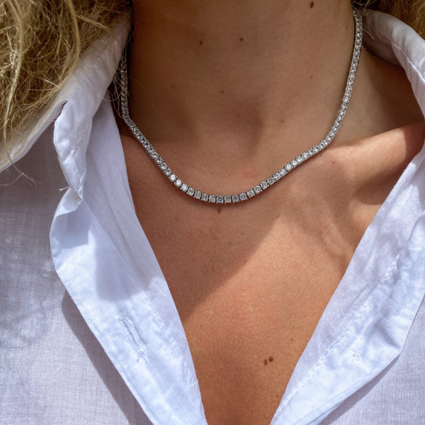 Model wearing The Tennis Necklace which is 16" in length made of Rhodium-plated brass covered with cubic zirconia stones.