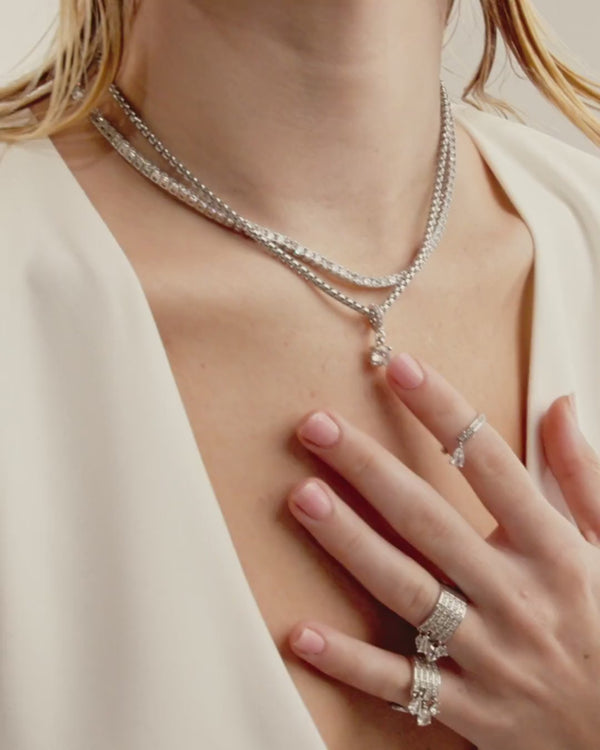 Video of a model wearing layered necklace set which includes the Tennis Necklace and stainless steel silver chain with The SOLITAIRE CLIP ON CHARM which is made of Pave clip on Stainless steel solitaire charm that is 20mm in length. She is also wearing the twin rings.