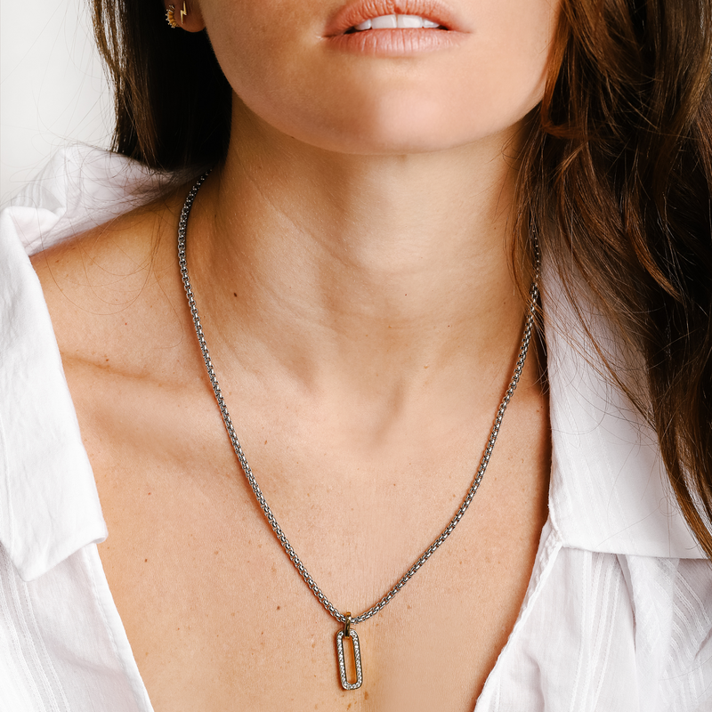 Model is wearing a tiny lightning earring and the clear mini huggies. She is also wearing the PROCIDA NECKLACE in Silver which is a 20" Stainless steel chain with an oval shaped gold plated and Zirconia charm. 