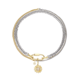 AMELIA LAYERED NECKLACE SET MIX:  A striking multi-strand necklace featuring mixed metal chains in gold and silver tones. The set includes a chunky curb chain, a delicate cable chain, and a textured rope chain, all adorned with a central clasp and a dangling charm showcasing a sunburst motif with shimmering crystals and a star accent.