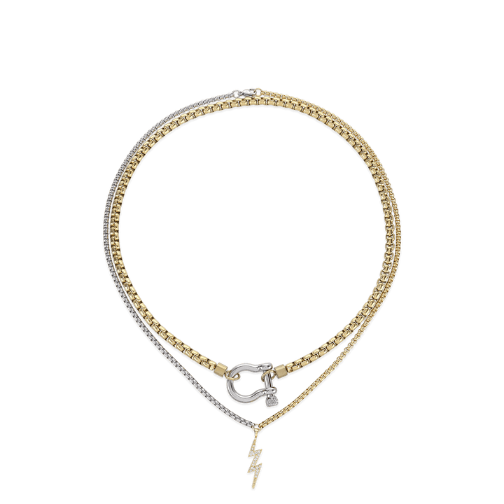 The Herradura Thunder Layered Necklace, a two-piece silver and gold necklace set featuring a box chain and a Cuban chain with a gold horseshoe clasp and a lightning bolt charm accented with diamond-like stones.