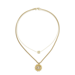 The I See You Necklace, a layered gold necklace featuring two chains. The shorter chain has a dainty square charm with an initial, while the longer chain showcases a striking sunburst pendant with an eye design encrusted in crystals. This mystical-inspired piece adds depth and personality, perfect for layering with other gold accessories or wearing solo for a bold look.