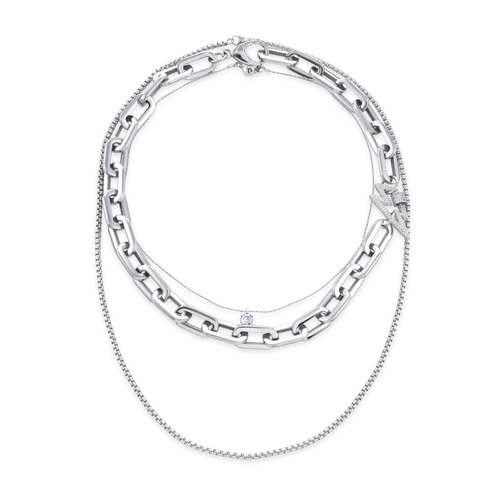 The SHINE PUERTO NECKLACE SET, which is a sophisticated layered necklace set featuring three unique silver-tone chains. This set combines chunky links, a delicate sparkling pendant, and fine detailing, offering a versatile and modern accessory for any occasion.