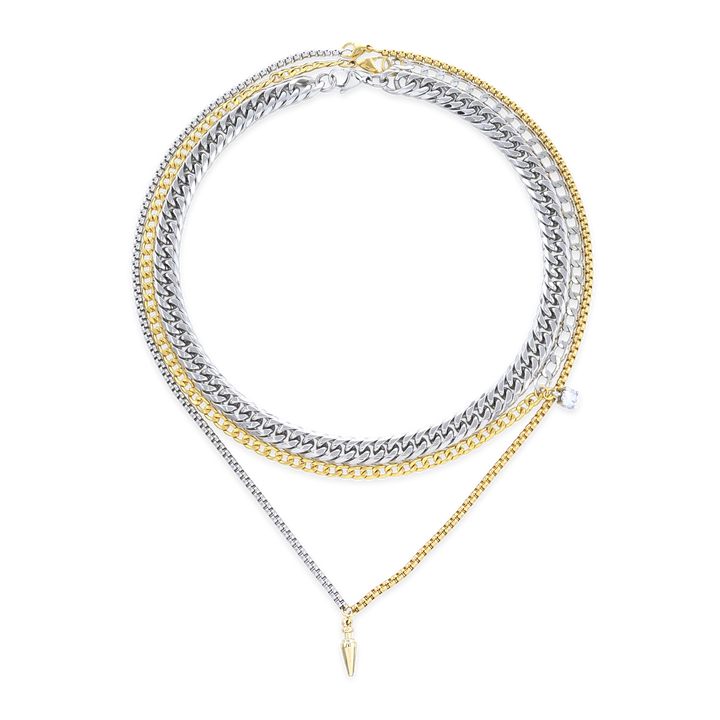 The Mulato Set, which is a four-piece layered necklace set, combines bold gold and silver chains with distinct textures and a drop pendant, offering a striking blend of modern elegance and statement-making versatility.