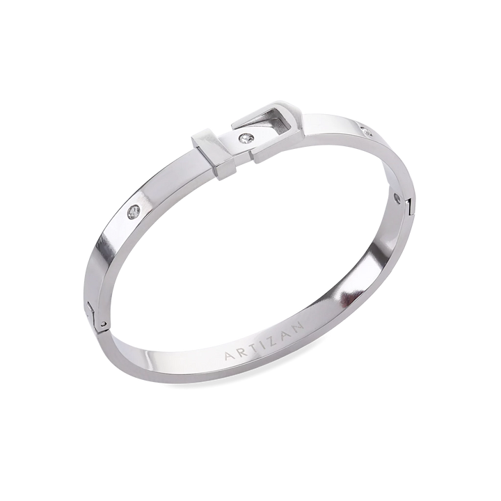 The BELT BANGLE, a stylish silver bangle featuring a unique buckle clasp design with sparkling diamond accents. ||| SILVER