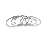 The Silver Gear Bracelet Stack, a five piece silver bracelet stack includes three unique bangle styles, one featuring a row of sparkling stones and another with a sleek, minimalist design. Two delicate tennis bracelets with shimmering stones.