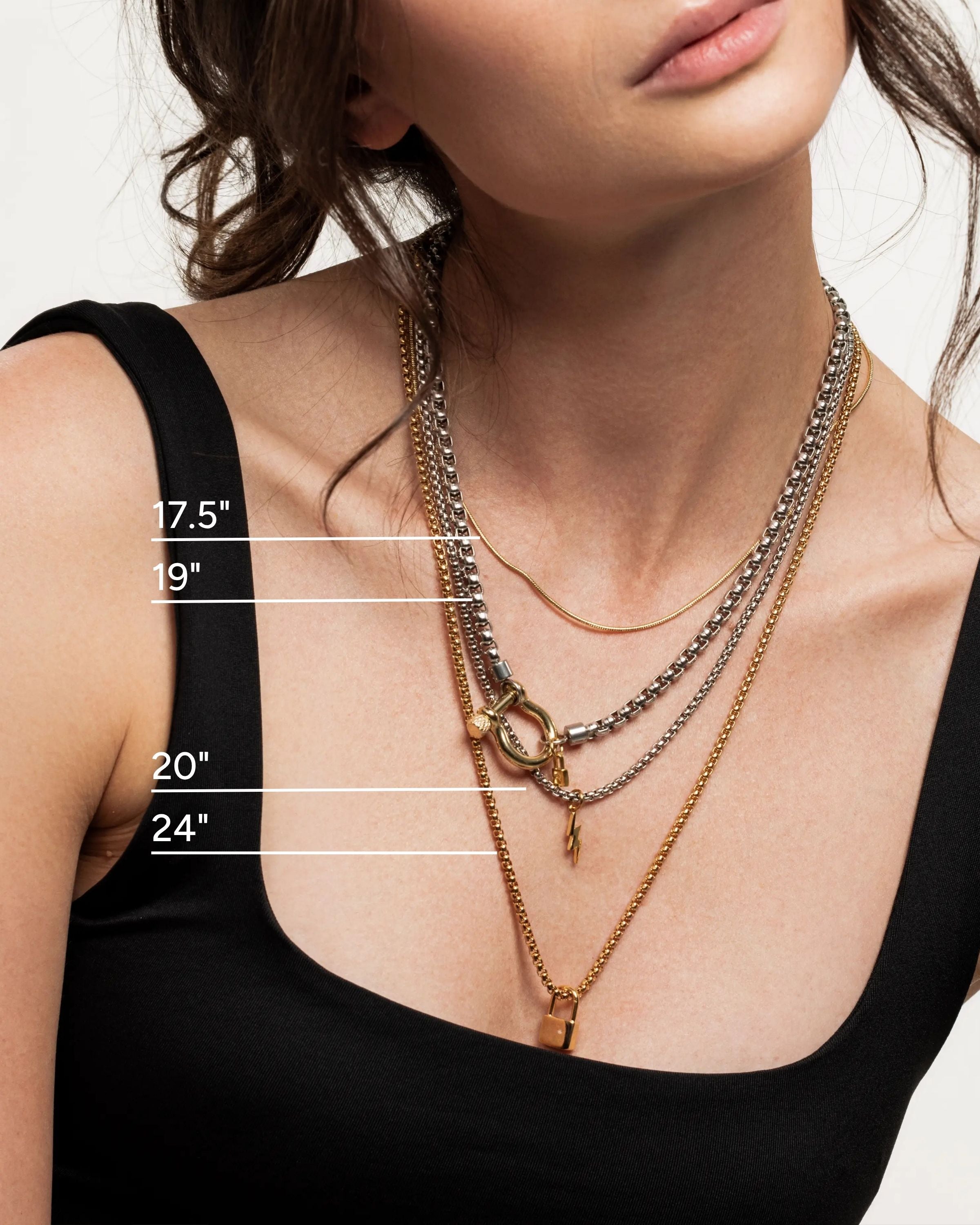 Model wearing the Herradura Lock Layered Necklace Set featuring four gold and silver mixed metal chains with a carabiner lock clasp and charm details. ||| GOLD