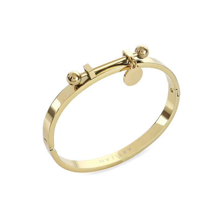 The Coins Bangle, a gold bangle bracelet with a unique toggle closure and a dangling coin charm. ||| GOLD