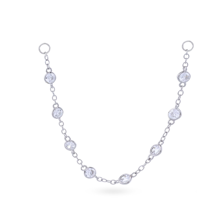 The Endless Diamond Earring Chain, a gold chain featuring seven bezel-set diamond-like stones. She is also earing a tiny lightning stud earring