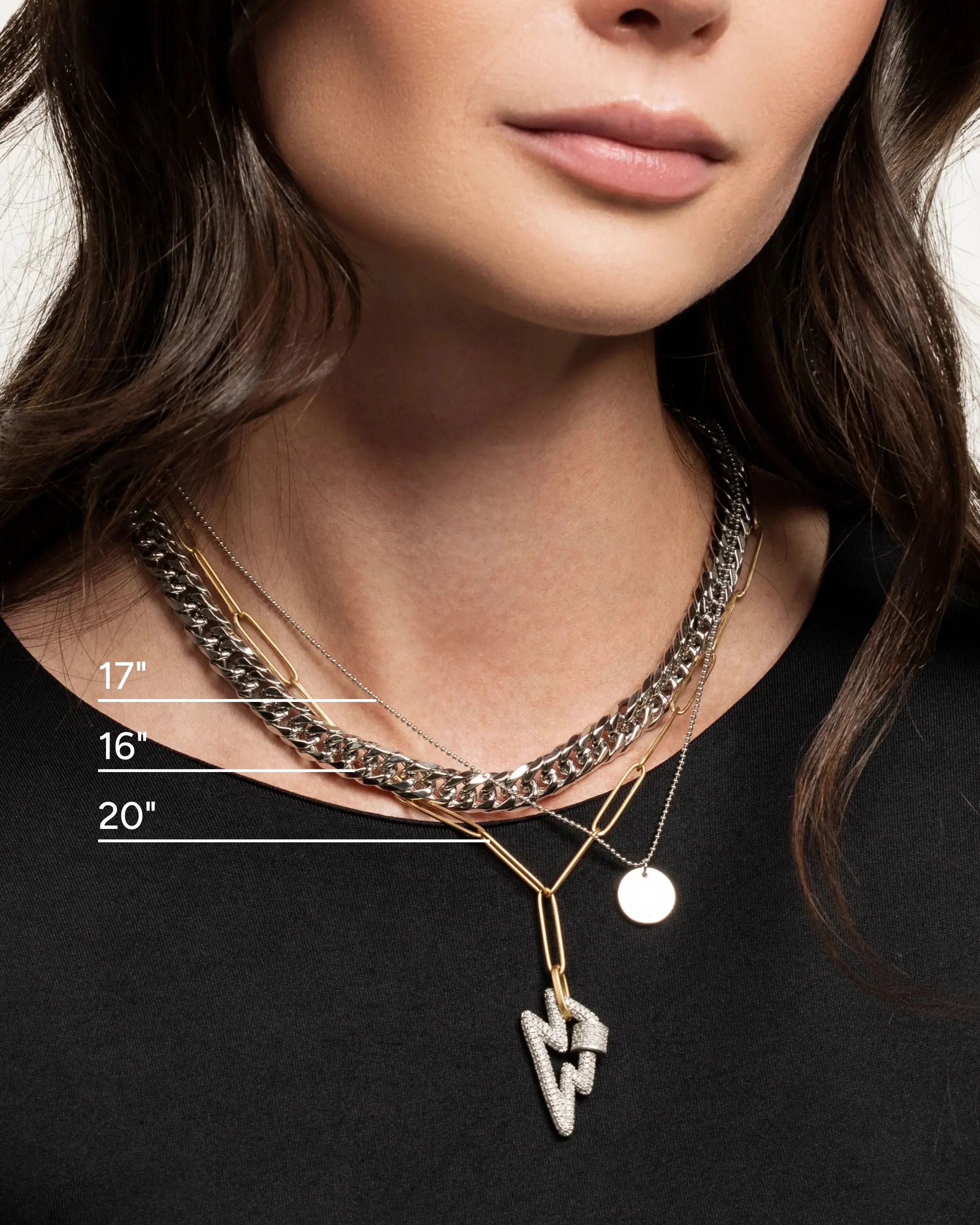 The Lightning layered necklace set, which is a three-piece layered necklace featuring a combination of silver and gold tones. It includes a chunky silver chain, a gold chain with a minimalist disc pendant, and a third chain with a striking lightning bolt pendant, creating a bold and dynamic look.