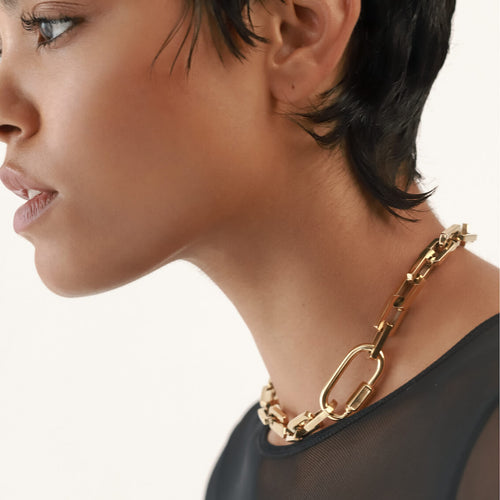 Model wearing the Carabiner Square Puerto Necklace, which is a striking gold chain necklace featuring a unique gold carabiner clasp.