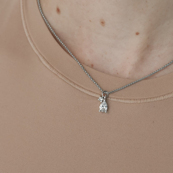 Model wearing the DROP ZIRCONIA NECKLACE which is made of 1mm wide Stainless steel chain with two 18K gold plated sterling silver pave drop charms., one is a mini zirconia charm.