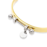 The Coin Bangle is a mixed-metal bracelet featuring a sleek gold band with silver-tone hardware, including a dangling coin charm and bold spherical accents. ||| MIX SILVER
