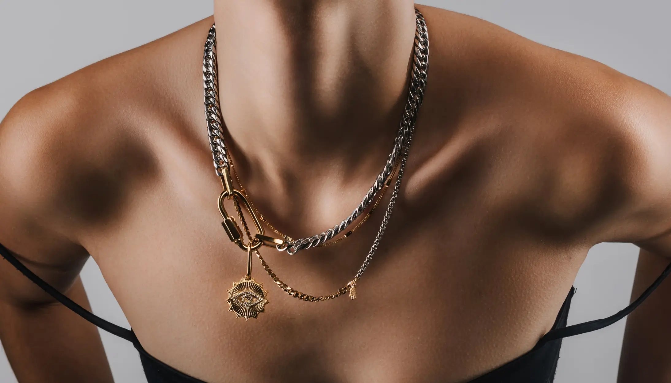 Model wearing the AMELIA LAYERED NECKLACE SET MIX, featuring layered gold and silver chains with a bold evil eye pendant.