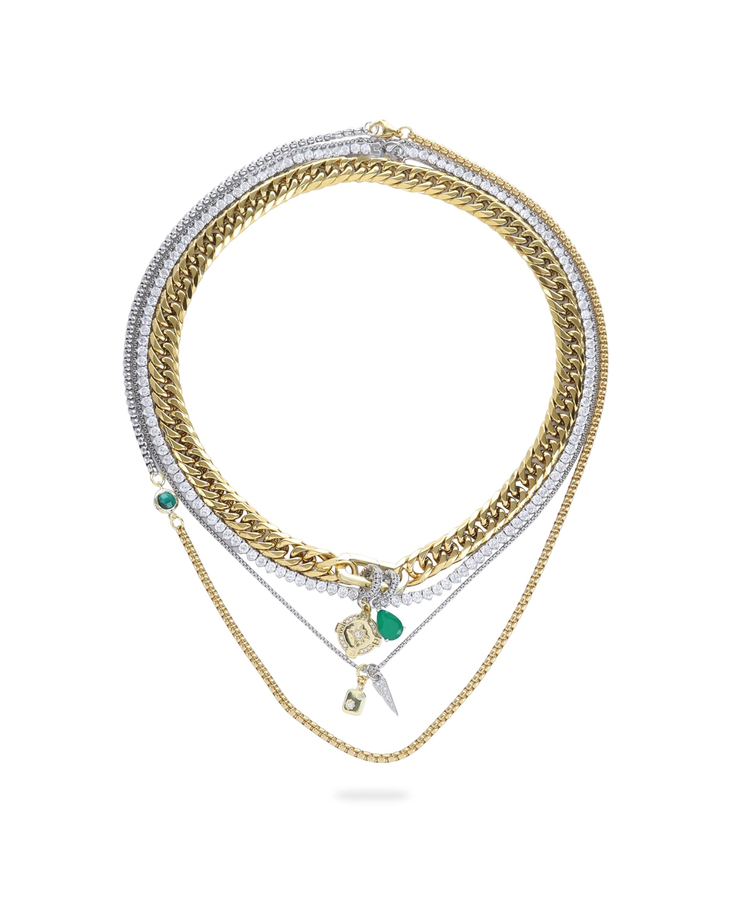 The Just Click Emerald Tennis Necklace Set, a four-piece gold and silver necklace set featuring a variety of chains with diamond-like accents, emerald accents, and a variety of charms.
