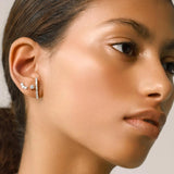 The Comet's Trail Earring, a three-piece silver earring set featuring a baguette and round cubic zirconia climber, a round cubic zirconia stud, and a three-stone round cubic zirconia ear stud.