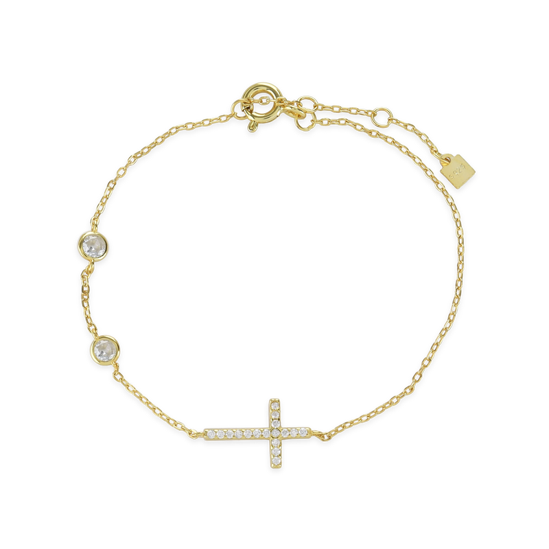 The Fine Cross Bracelet which is a gold bracelet featuring a dainty chain adorned with three shimmering diamonds and a cross charm set with sparkling diamonds.