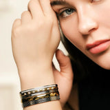 Model wearing the Intense Stack, a five-piece gold and silver bracelet stack featuring bangles with various diamond-like accents and textured designs.