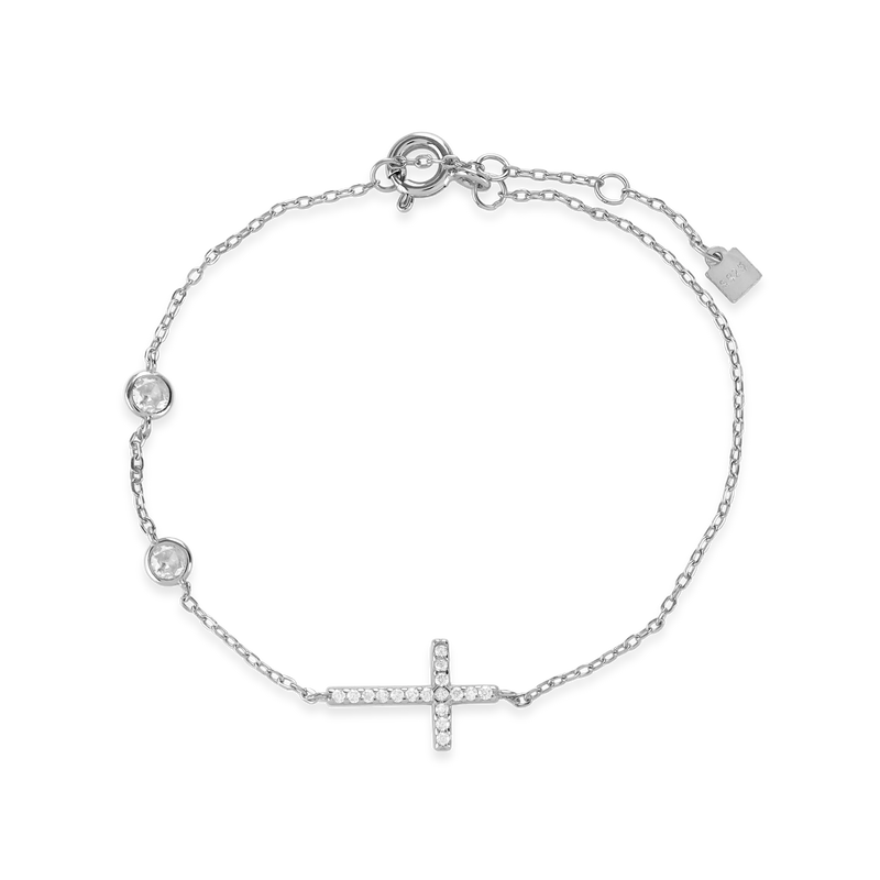 The Fine Cross Bracelet which is a gold bracelet featuring a dainty chain adorned with three shimmering diamonds and a cross charm set with sparkling diamonds.