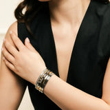 Model wearing the Intense Stack, a five-piece gold and silver bracelet stack featuring bangles with various diamond-like accents and textured designs.