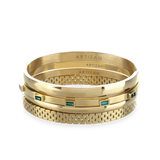 The Queen's Crown Bracelet Stack, a four-piece gold bracelet stack featuring bangles with a variety of accents, including the word "ARTIZAN," emerald accents, and a textured design.