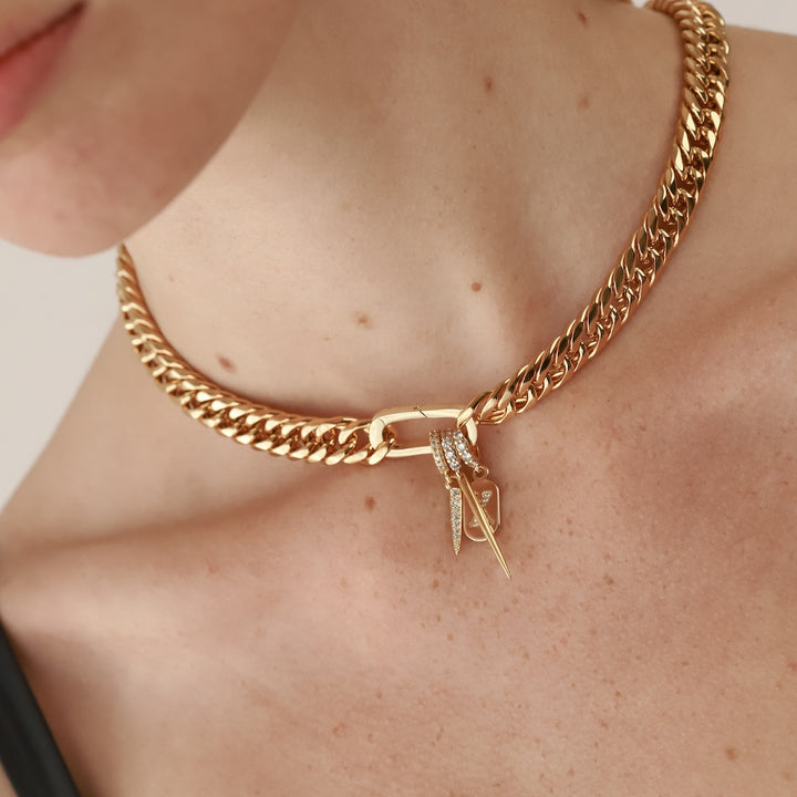 Model wearing the JUST CLICK SPIKE CHAIN made of 18k gold plated stainless steel and has two charms. The 18k gold plated spike charm and the JUST CLICK NEEDLE CHARM which is made of Sterling silver 18k gold plated spike pave charm. The link to where the necklace goes is encrusted with zirconia.