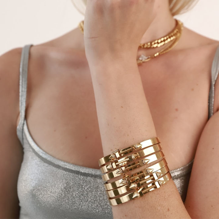 Model wearing the JUST CLICK NUT NECKLACE SET and 6 pieces of The Sasha's bangle made of 18K gold plated 316L Stainless steel. It has a bar design on top with two spikes on each end. It has zirconia details and triangle charm as well. ||| GOLD
