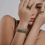 Model wearing the LINKED-UP BRACELET featuring a chunky gold link design with a secure clasp and a stacked bracelet and rings featuring gold and diamond accents, styled with a minimalist look.