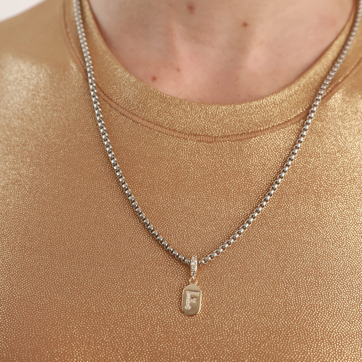 Model wearing a stainless steel chain with the LETTER JUST CLICK CHARM which is made of gold filled encrusted zirconia letter "F" initial. ||| A/GOLD