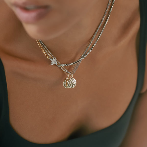 Model wearing the FUSION IRIS NECKLACE is made of mixed Stainless steel chain and18k gold plated cuban chain connected with a Sterling Silver lotus shaped zirconia charm. She is also wearing three necklaces with the DALMATIAN BULKY CHARM. 