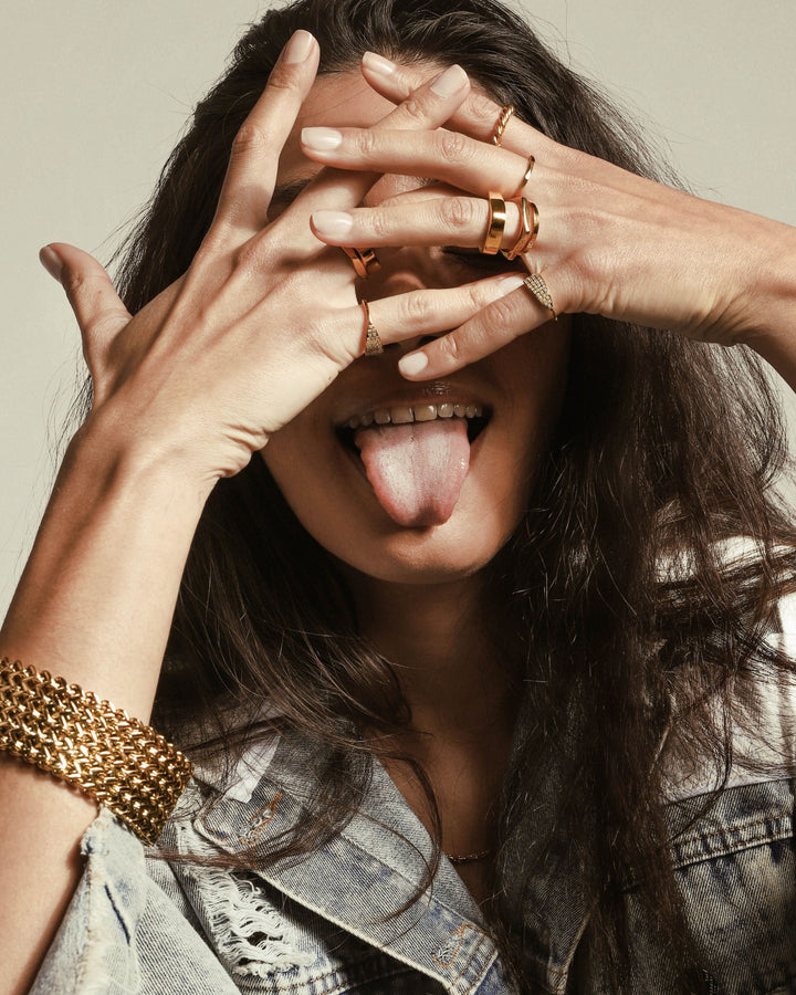 Model earing The Rhombus RING which is an 18k Gold plated pentagon shaped ring. She is also wearing other artizan rings and the braided chain cuff.