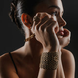 Model wearing Artizan Joyeria's gold chain choker, LINKED-UP BRACELET, and textured gold ring, styled with a chic and minimal look.