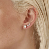 Model wearing the Dancing Ear Cuff, a silver ear cuff featuring delicate cascading chains and shimmering diamond accents and also two more earrings with diamonds.