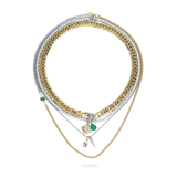 The Just Click Emerald Tennis Necklace Set, a four-piece gold and silver necklace set featuring a variety of chains with diamond-like accents, emerald accents, and a variety of charms.