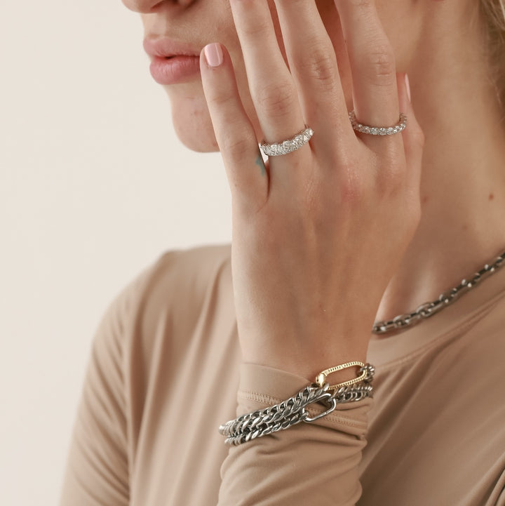 The JUST CLICK BRACELET, a bold and chunky layered bracelet stack in mixed metals with silver chains and a single gold link for added contrast, worn on a model's wrist. ||| MIX