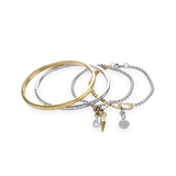 The Mix Gear Bracelet Stack, a four-piece gold and silver bracelet stack featuring two bangles and two chains with a variety of charms, including a teardrop charm, a spike charm, and a disc charm accented with diamond-like stones.