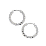 The Wraparound Maxi Huggies, a pair of silver hoop earrings completely encrusted with sparkling cubic zirconia stones.