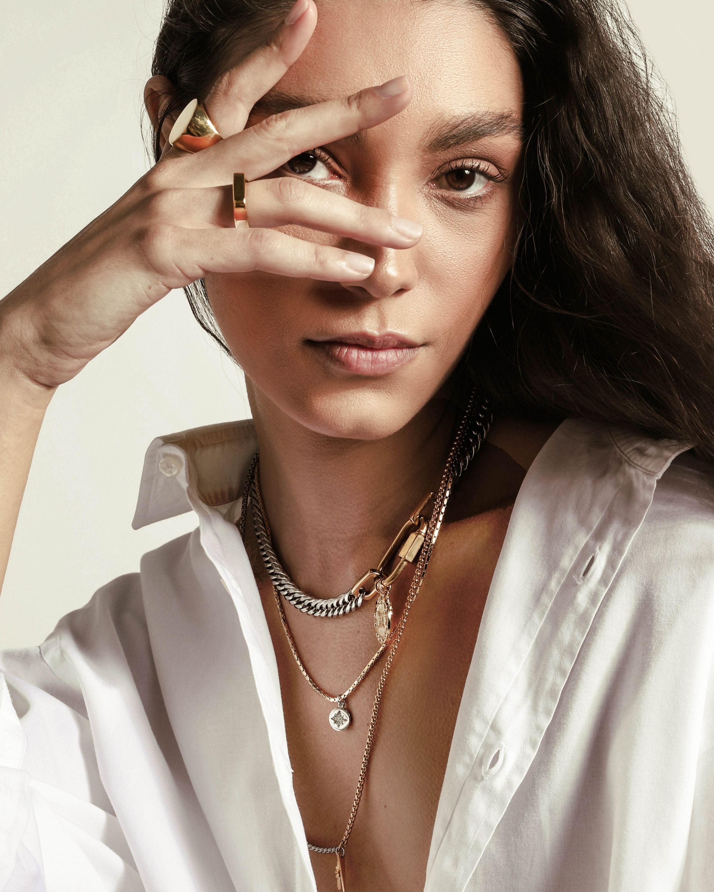 Model wearing the Anne Zodiac Necklace which is a three pieces layered necklace set. Includes one silver chain with 18k gold plated carabiner and Gold Filled LEO Zodiac with Micro Pave Constellation charm, thin gold necklace with silver circle charm and another long necklace in half gold and silver with spike shaped charm and Gold Plated Micro Pave Studded Star.  |||