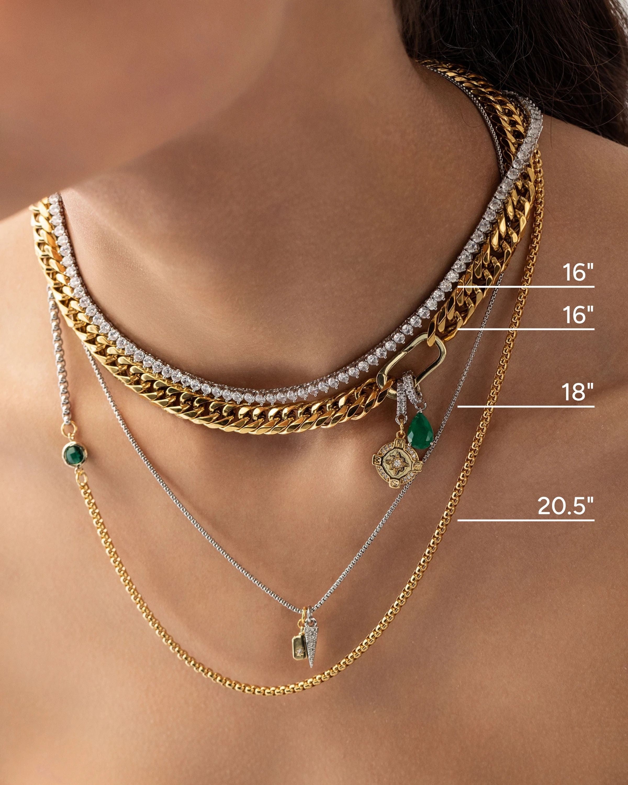 Model wearing the Just Click Emerald Tennis Necklace Set, a four-piece gold and silver necklace set featuring a variety of chains with diamond-like accents, emerald accents, and a variety of charms.