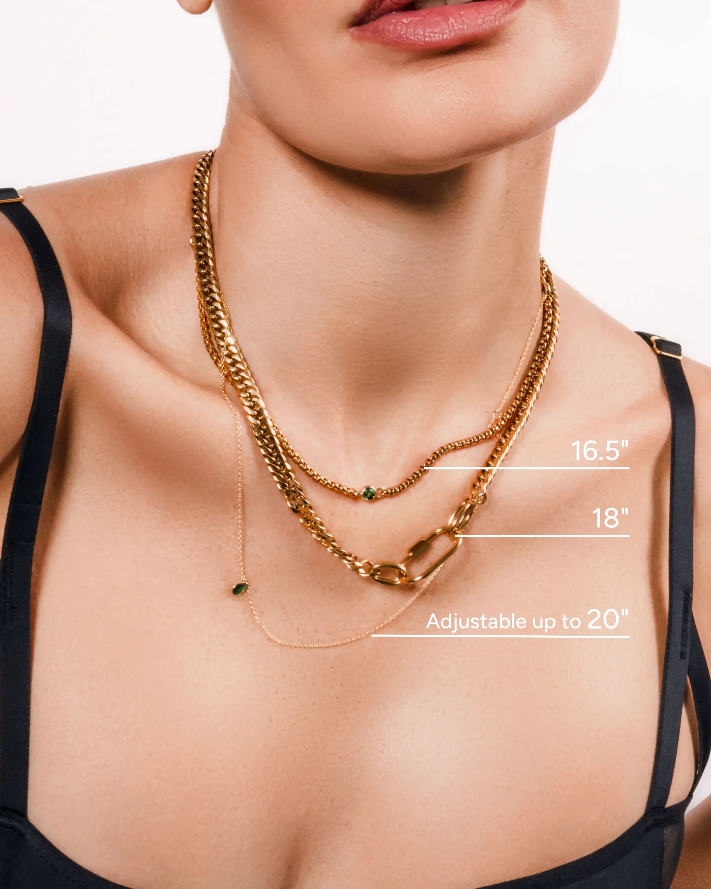 Model wearing the Sleek Carabiner Emerald Layered Necklace Set featuring four gold chains with emerald stone details and a bold carabiner clasp.
