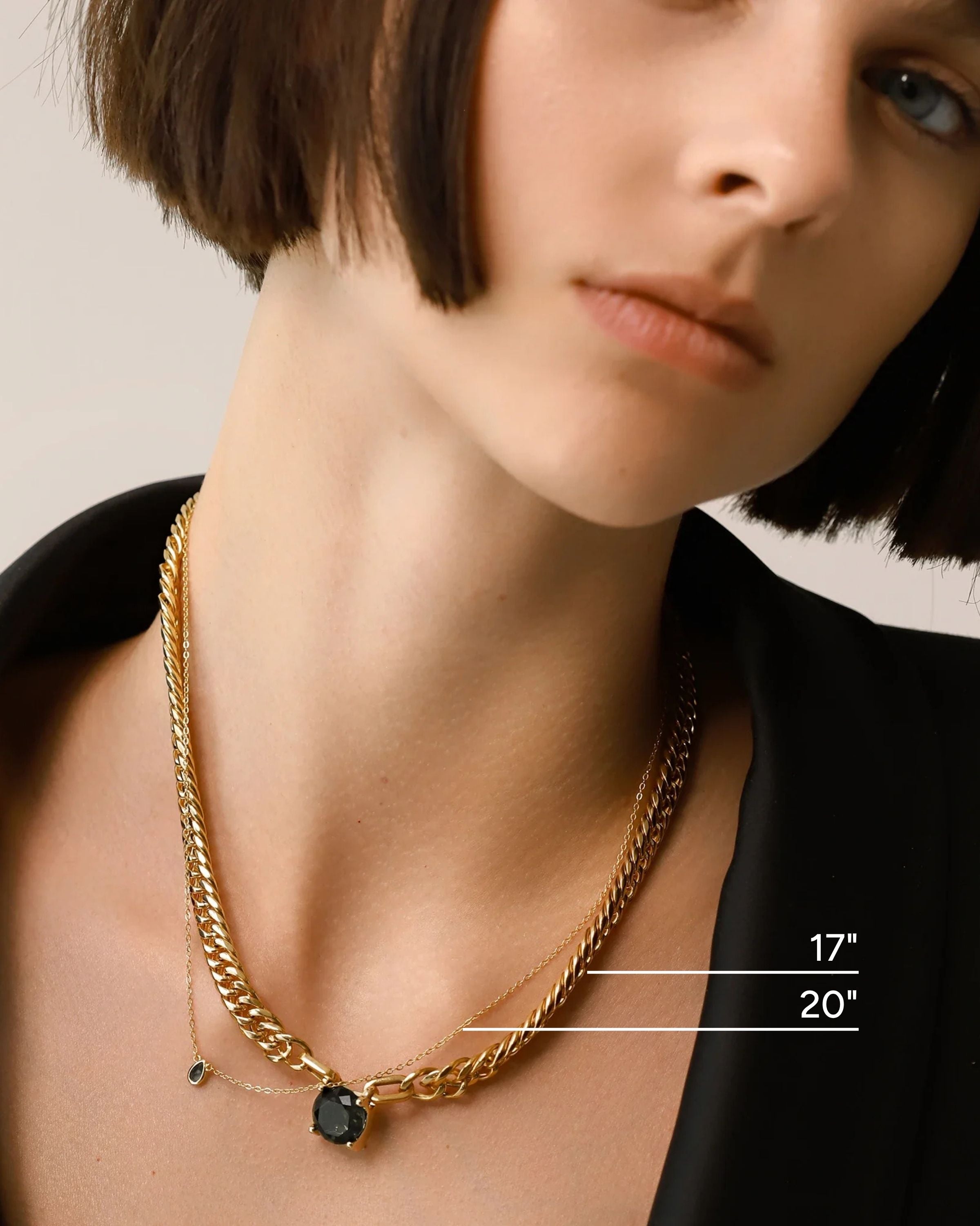 Model wearing the Emerald Dot Necklace Set, a two-piece gold necklace featuring a delicate chain with a single emerald pendant and a matching choker chain.