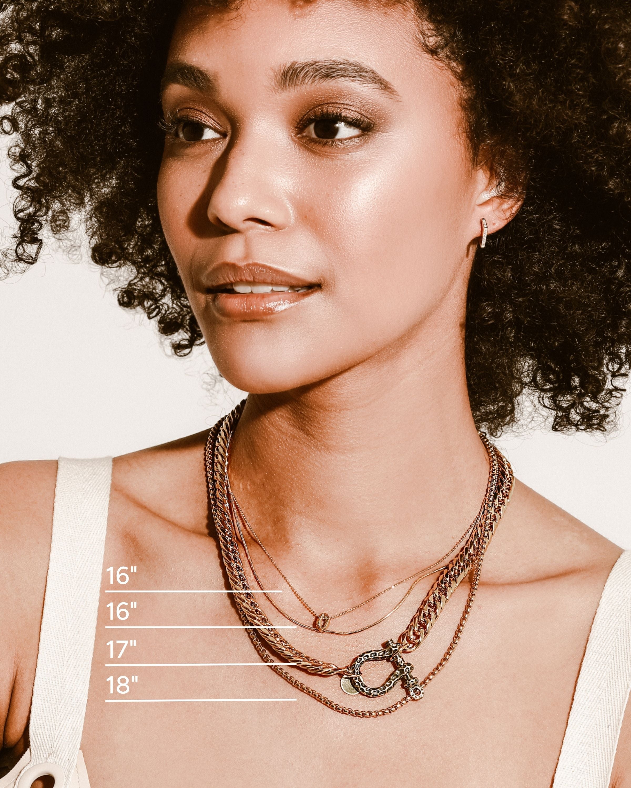 Model wearing the Le Giraffe Herradura necklace set which includes 3 separate chains, chunky gold chain with herradura clasp designed like giraffe skin with a small gold disc charm, short gold thin chain and long thin gold chain with circle charm.