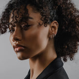 Model wearing the Tiny Huggies Hoop, a pair of small silver hoop earrings that feature a row of sparkling cubic zirconia stones set in a  pointed, triangular pattern. ||| SILVER/5mm