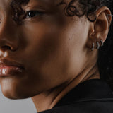 Model wearing the Tiny Huggies Hoop, a pair of small silver hoop earrings that feature a row of sparkling cubic zirconia stones set in a  pointed, triangular pattern. ||| SILVER/5mm