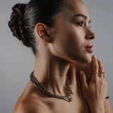 Model wearing a Tennis Earring Chain, a single long gold chain earring with tiny sparkling stones. She is wearing the just Click Nut Necklace set and 3 artizan rings. ||| GOLD