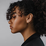 Model wearing the Mini Clear Huggies, a pair of small gold hoop earrings with sparkling clear cubic zirconia stones.||| GOLD